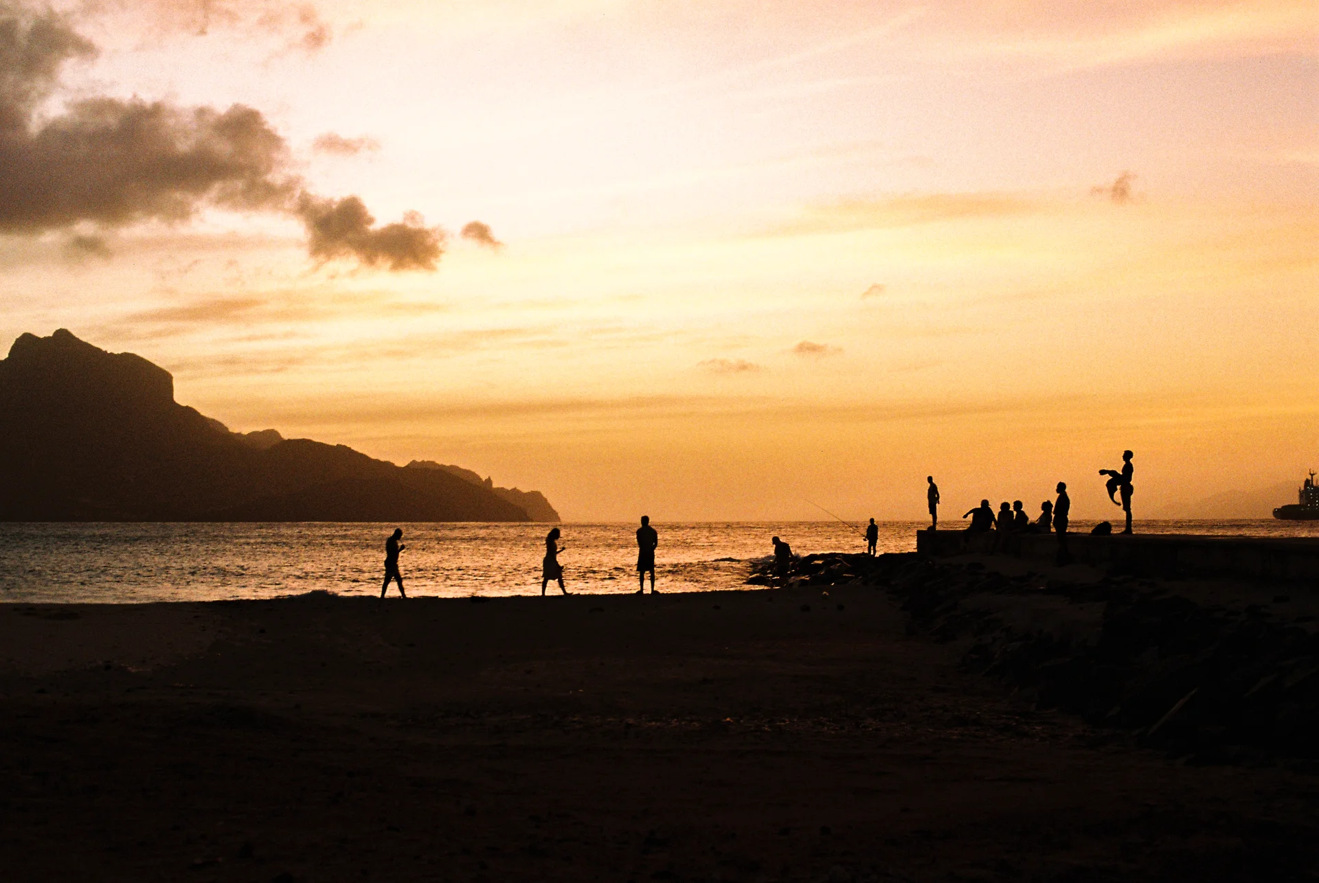 People silhouetted on the shoreline at sunset in São Vicente, Cape Verde