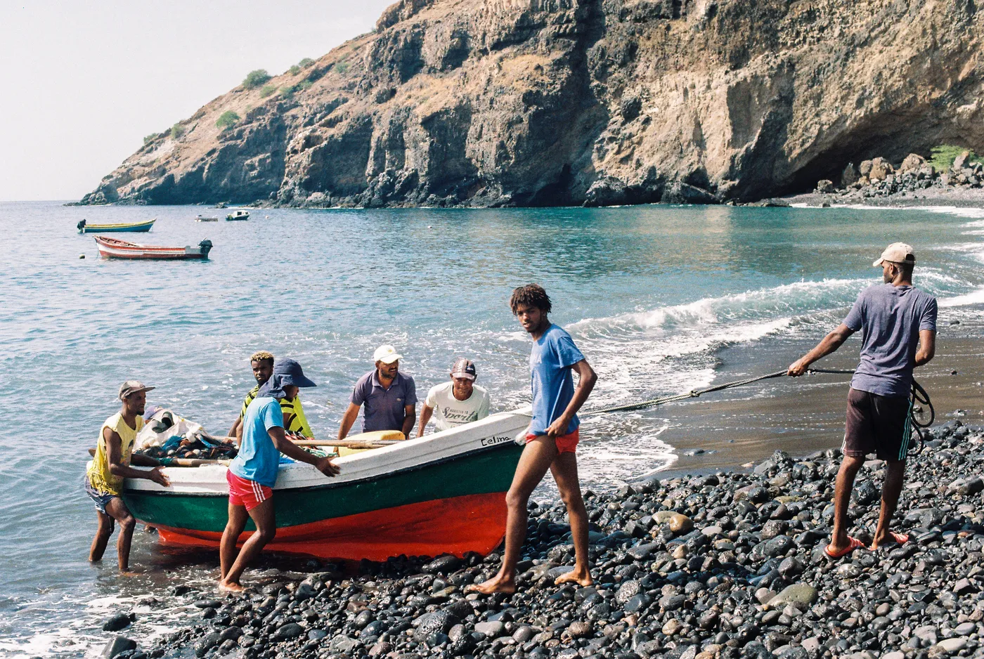 Fishermen launching a boat from a black sand beach in Santo Antão, Cape Verde