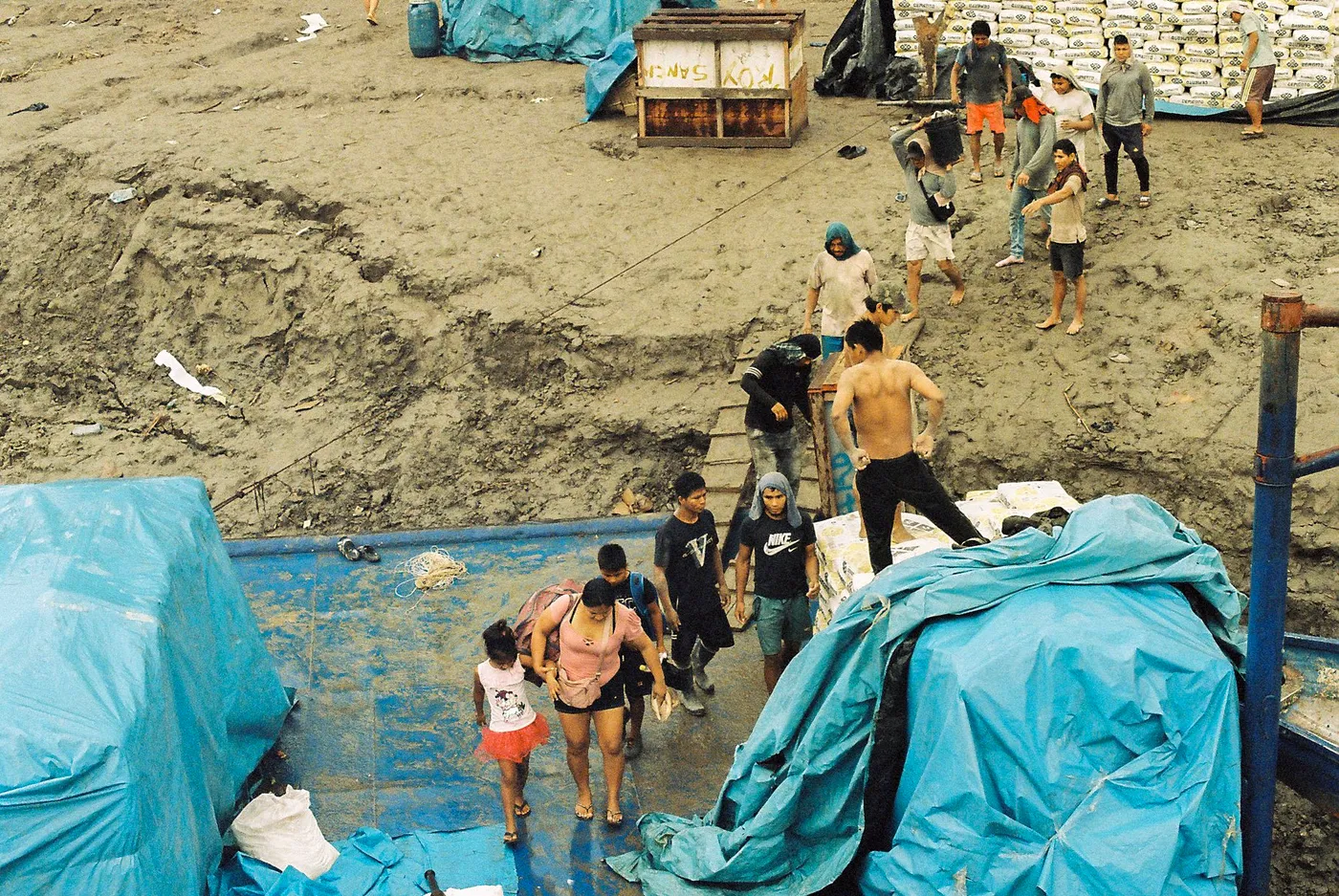 Porters carrying sacks up a muddy riverbank on the Amazon