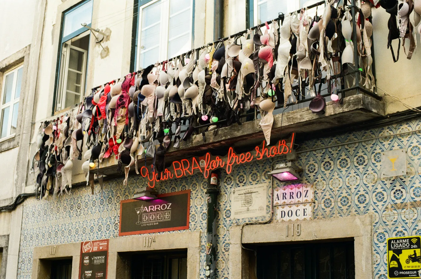 Bras strung from a bar balcony above a tiled façade in Lisbon